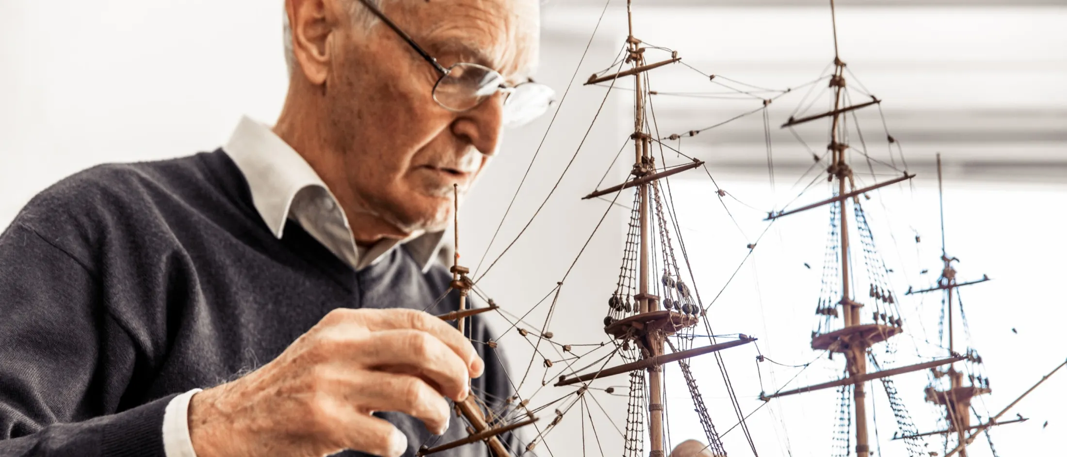 Man building model replica of an old galleon sail boat.