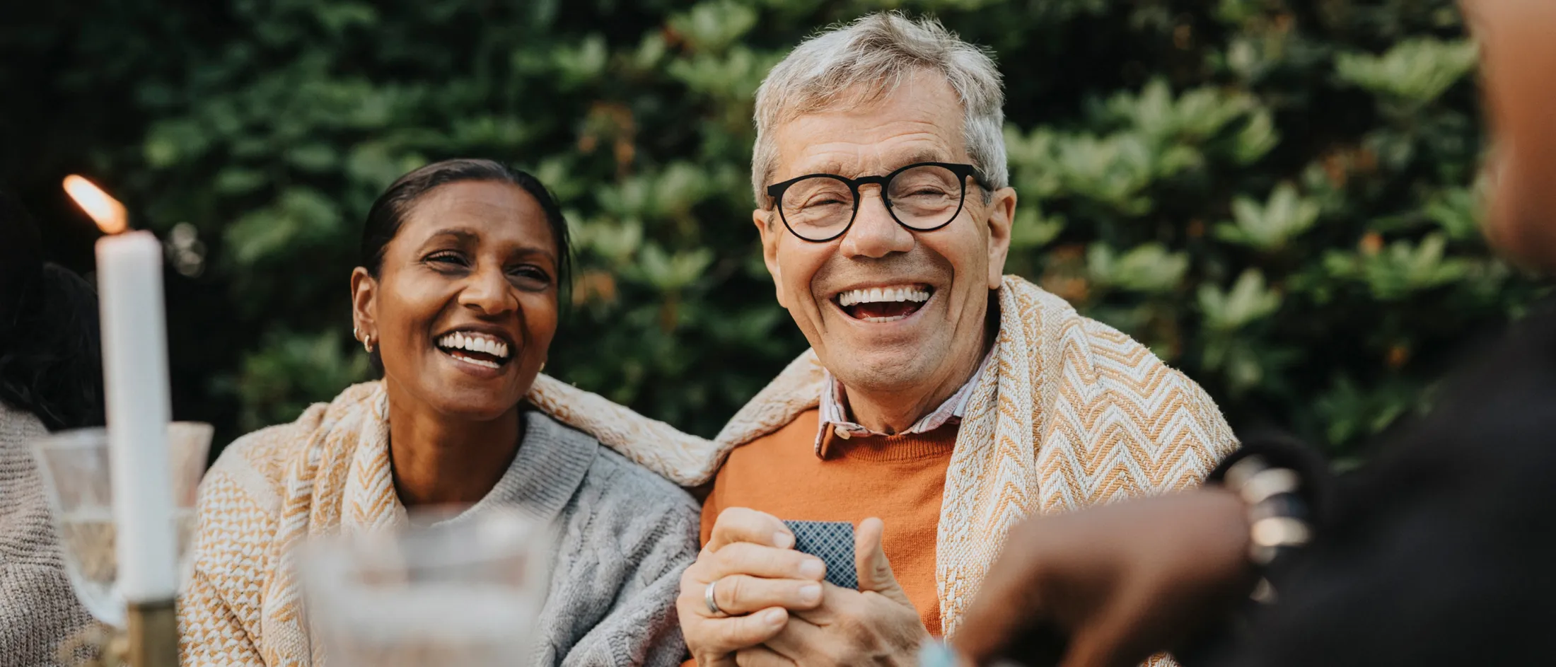Man wearing glasses with a woman and man sitting at a table