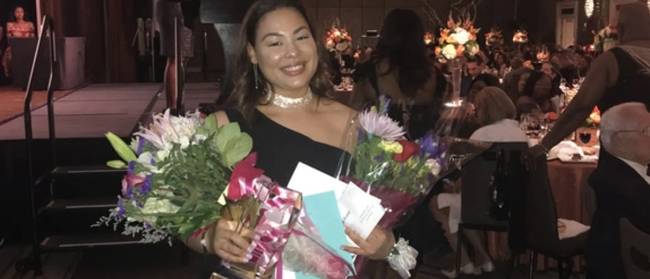 Woman nurse holding flowers and her award smiling for the camera