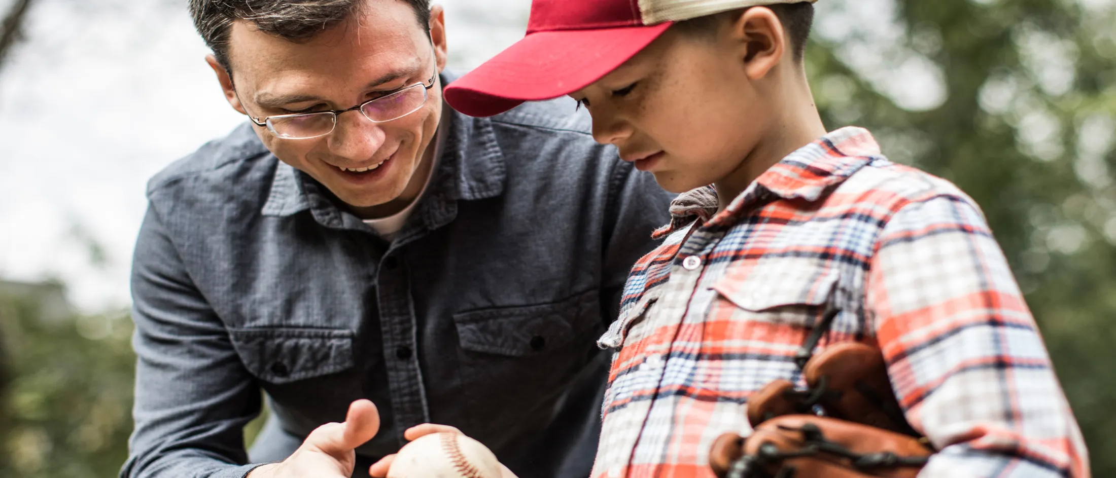 Man wearing glasses and playing baseball with a boy