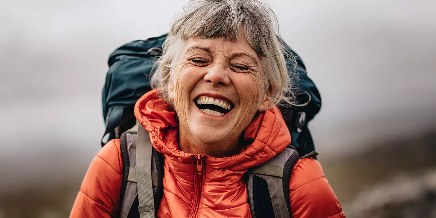 Woman wearing a hiking backpack smiles.