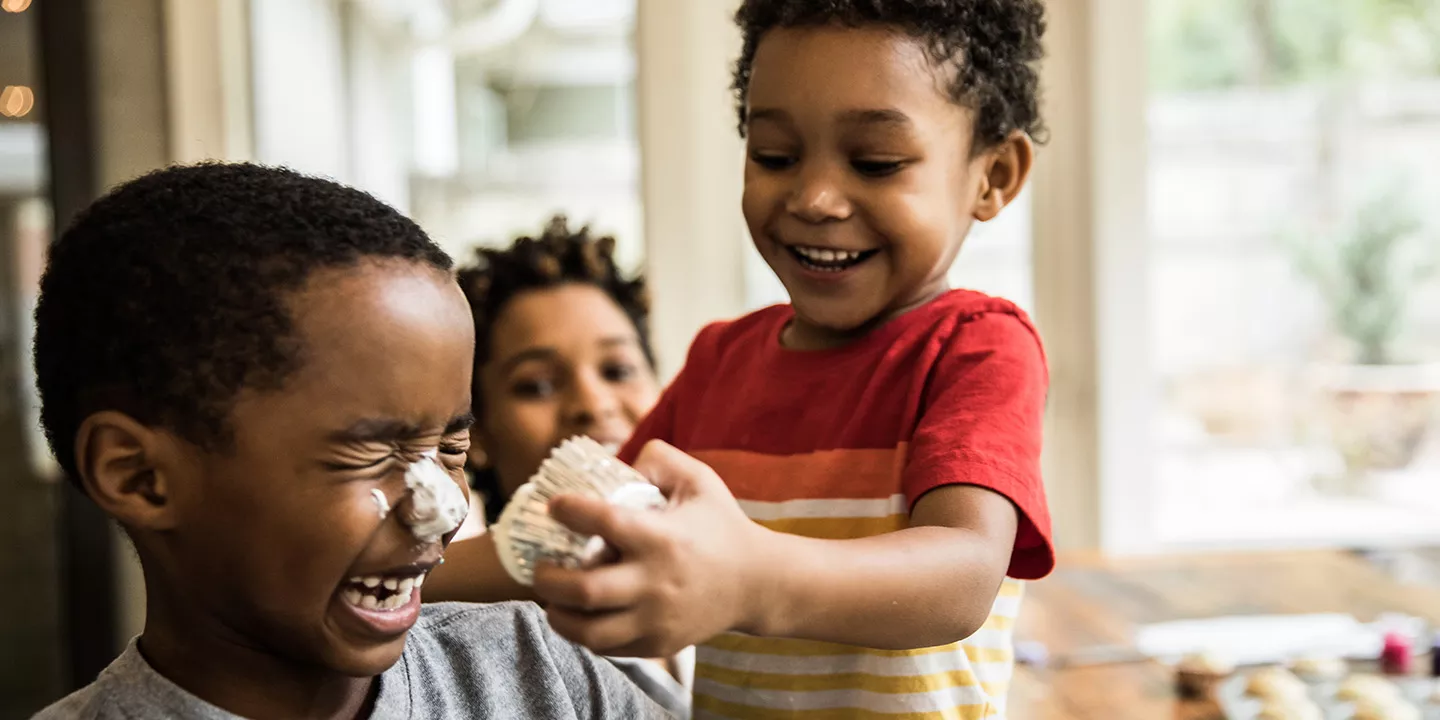 Toddler smushes cupcake on brothers nose.