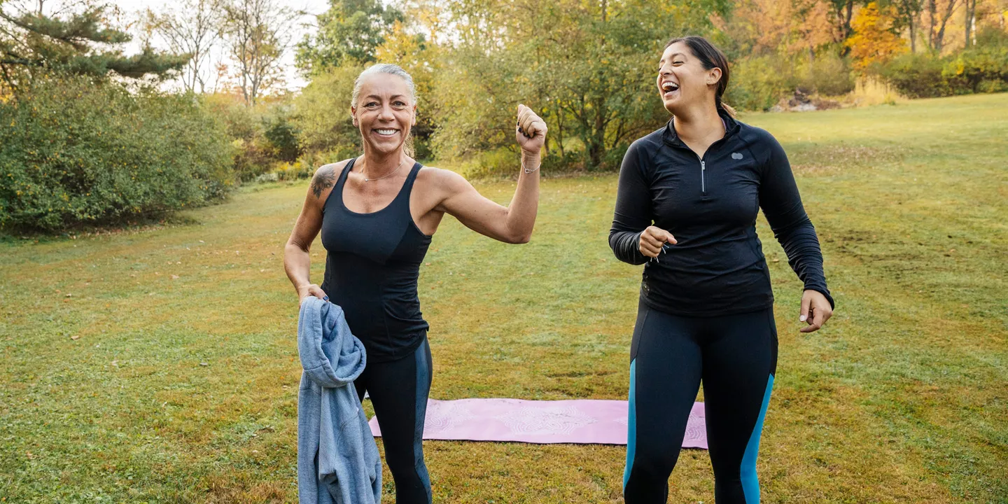 Two woman laughing in the park while exercising.  