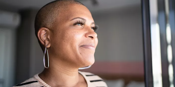 Bald woman looks confidently out window