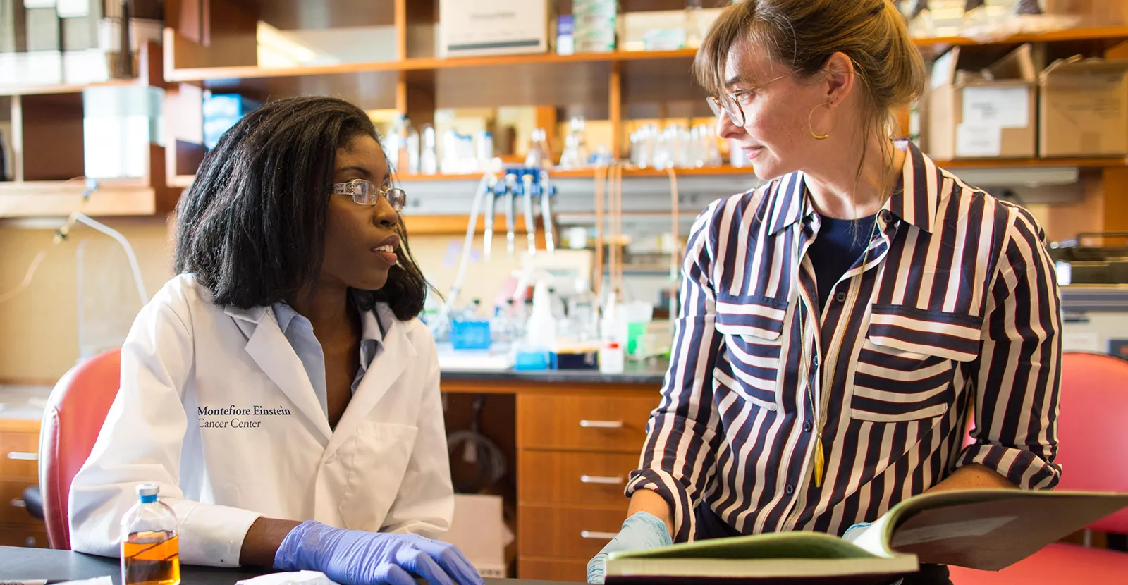 Instructor discussing text with student in laboratory.