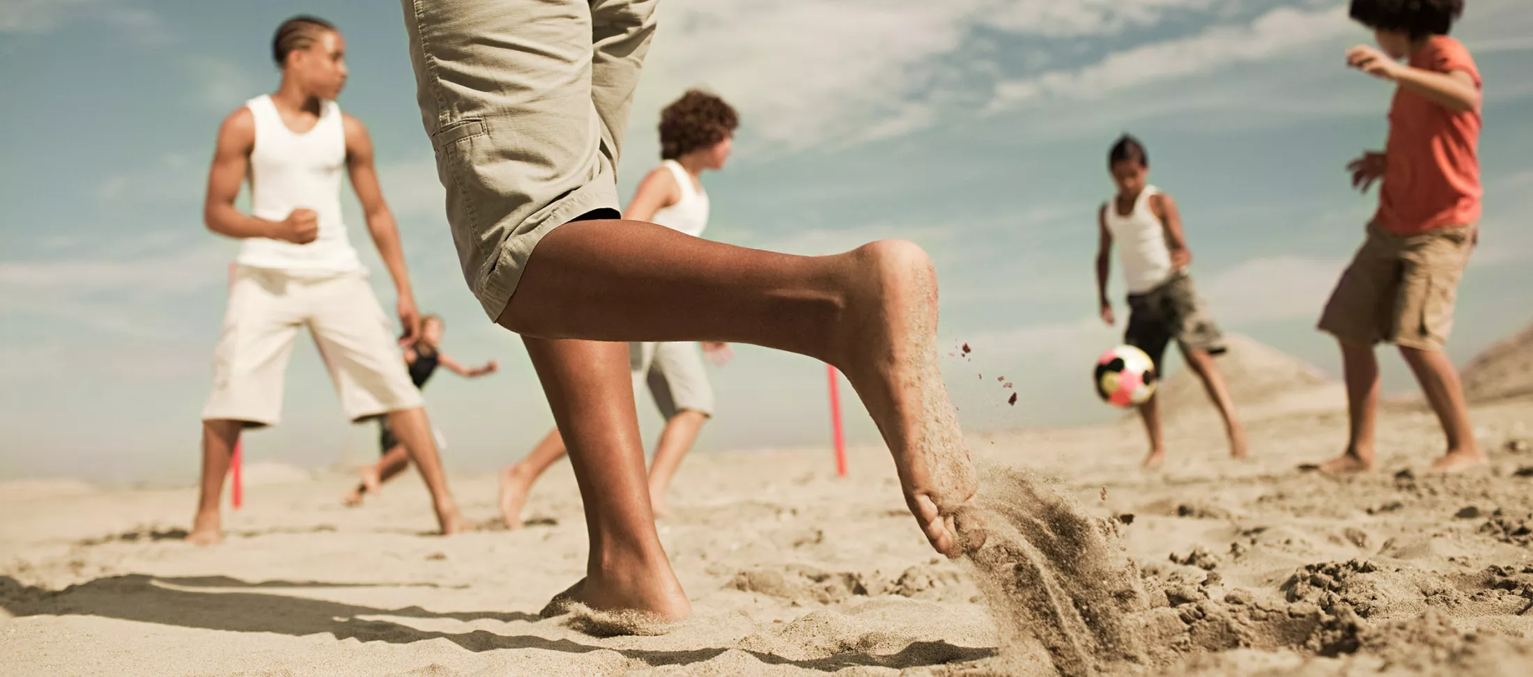 Boys playing football on a beach.