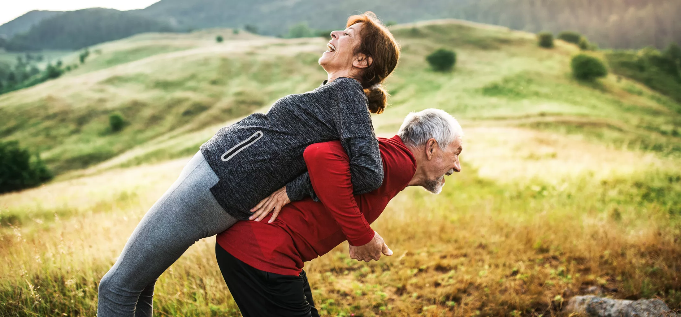 An old man and woman stretching by the lake outside in the countryside.