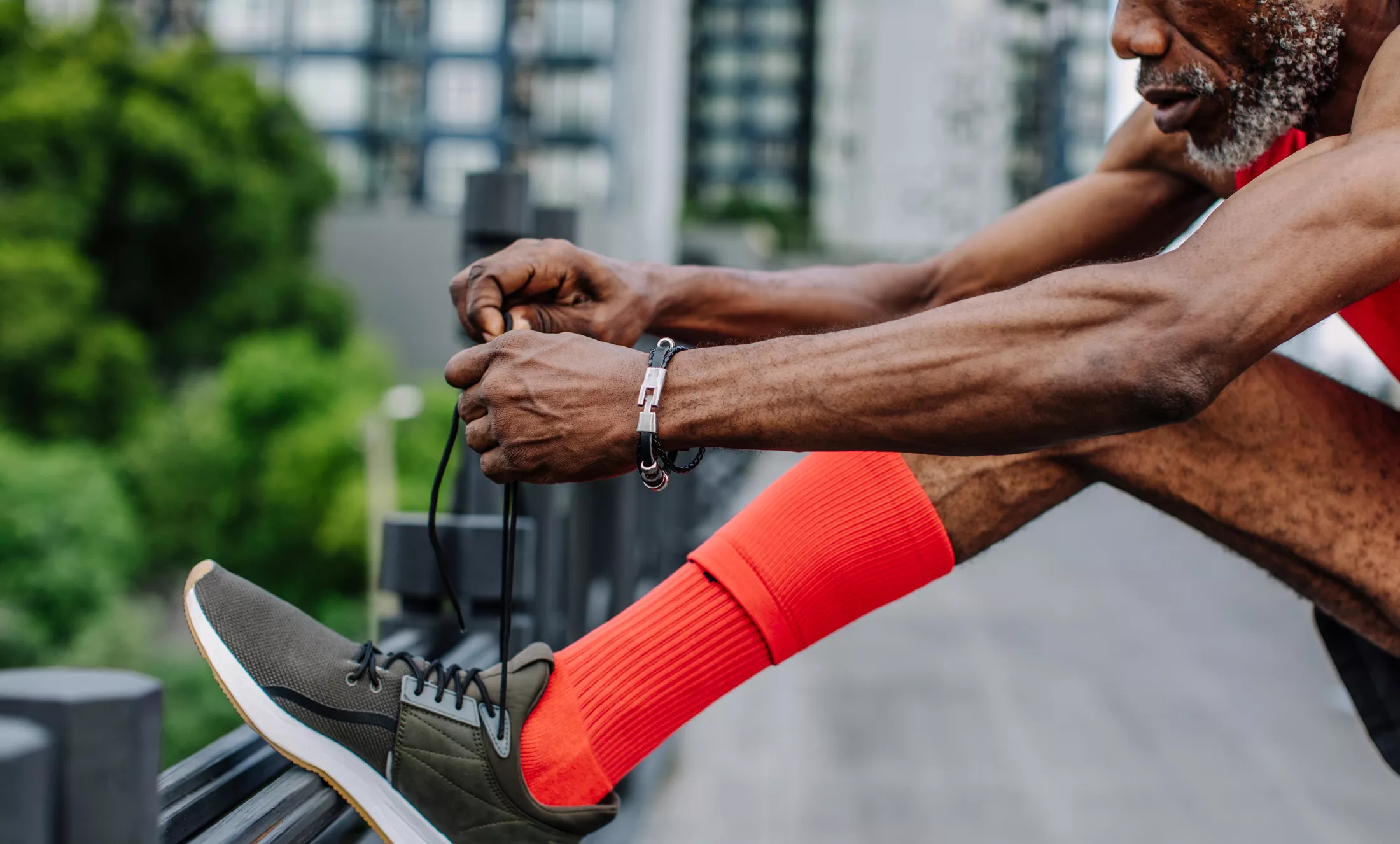 Man tying shoelaces on his sneakers before an outdoor cardio workout.