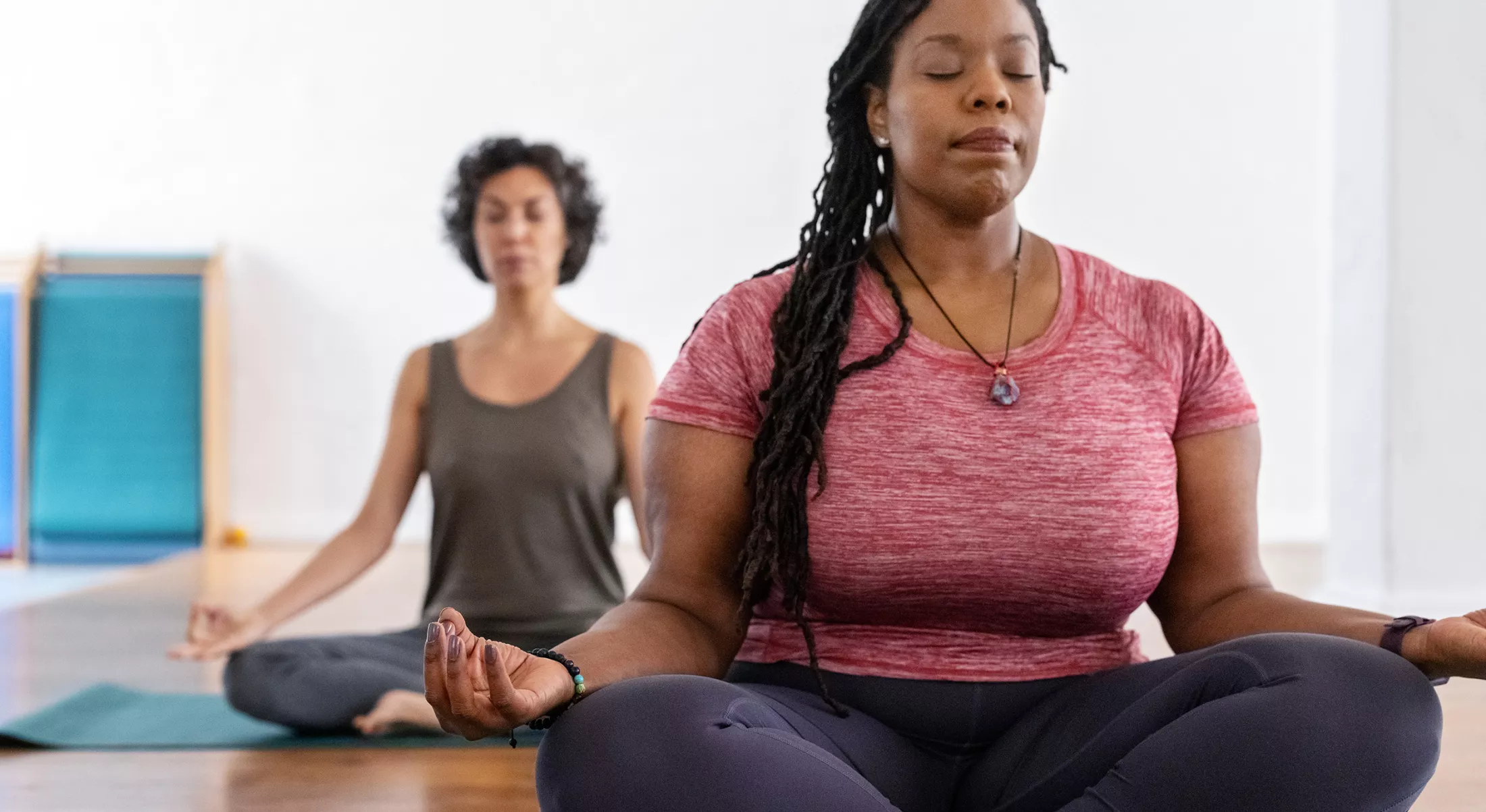 Two women mediatring and doing yoga in a studio
