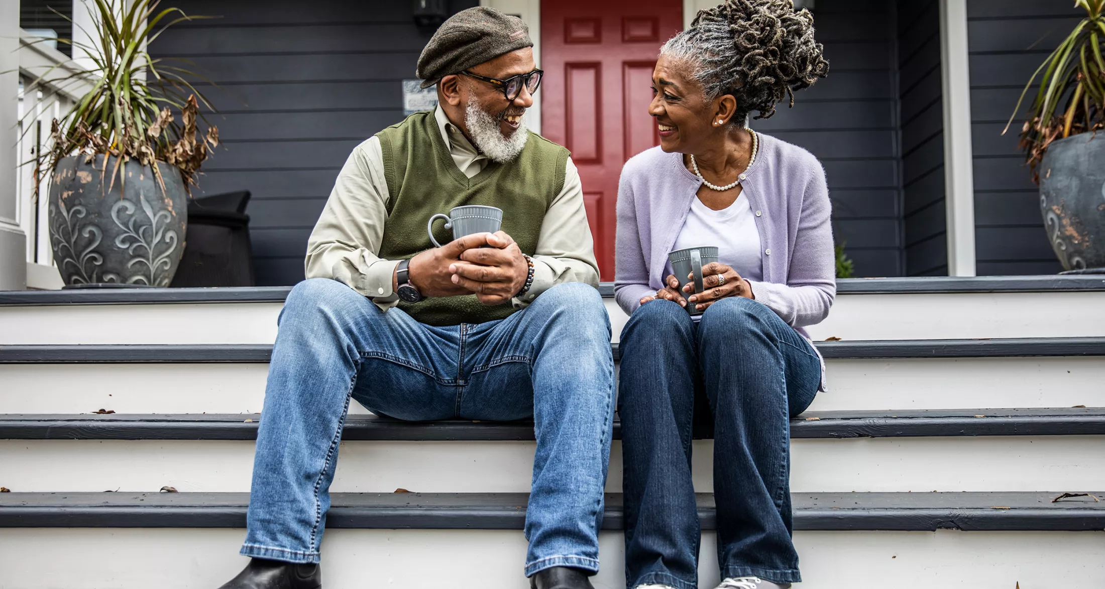 Senior couple having coffee in front of suburban home