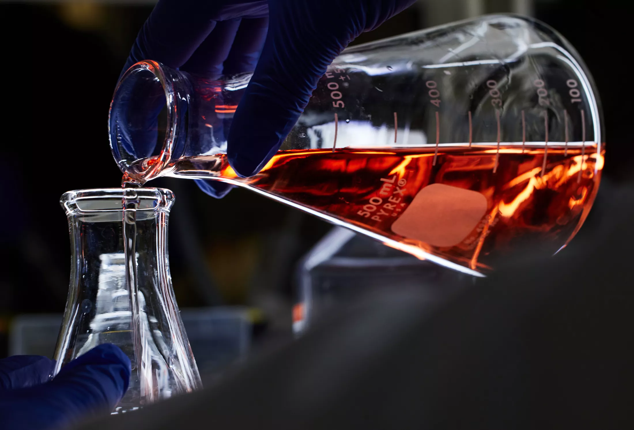 A beaker pouring liquid into another beaker