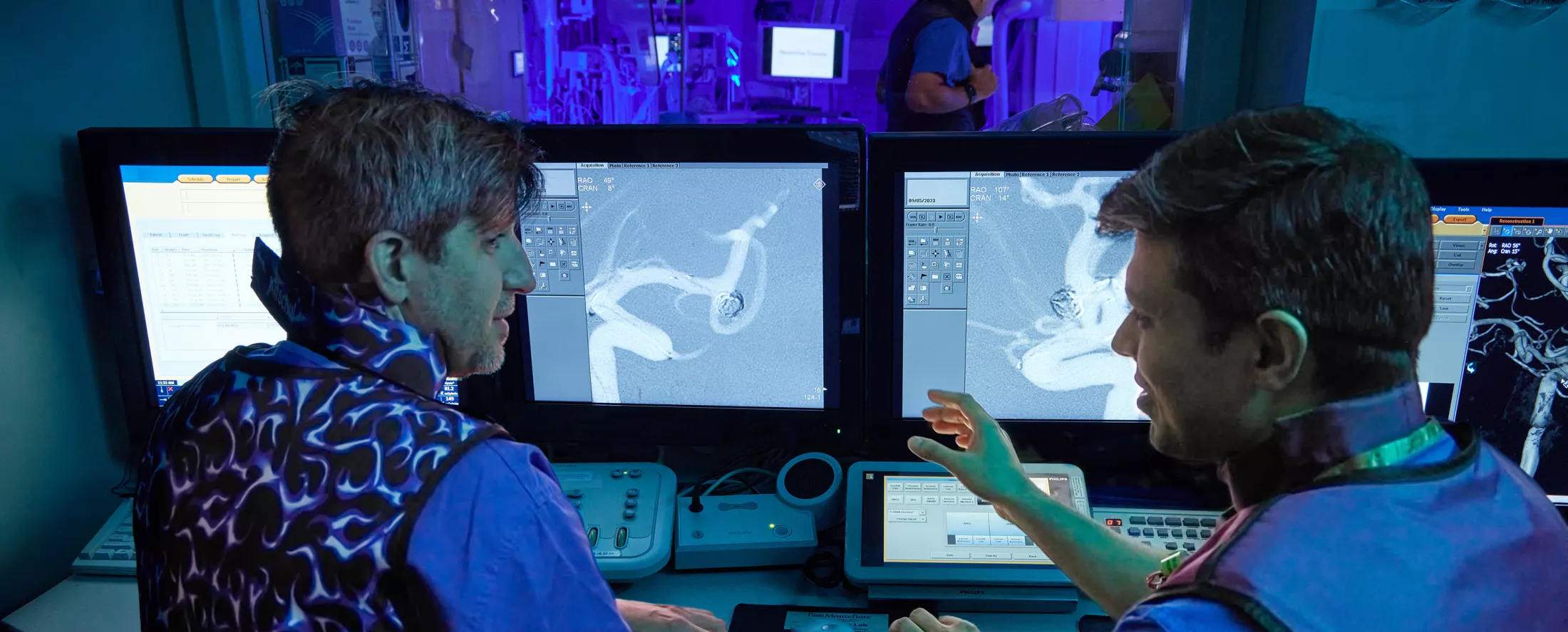 Two physicians inside a hospital lab filled with equipment and screens