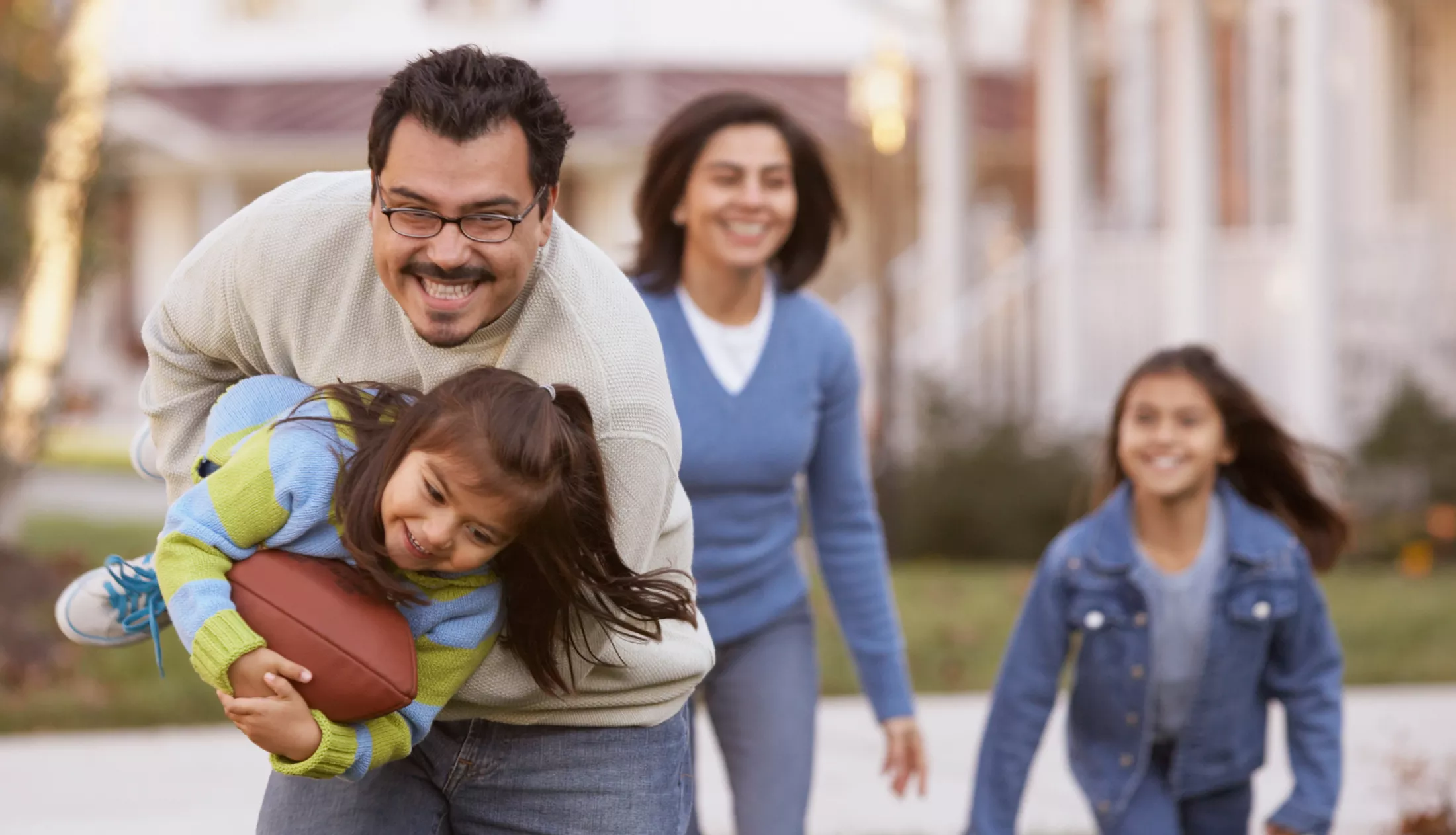 Family playing football in front yard