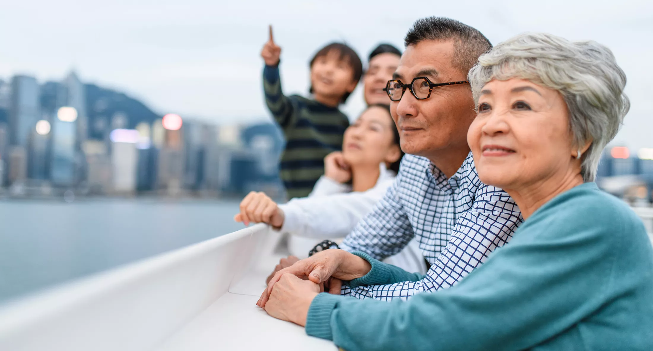 Smiling family outside large city watching something in the distance