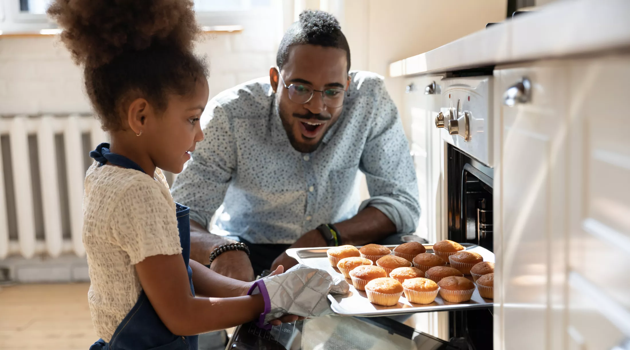 A father and daughter baking muffins in the kitchen