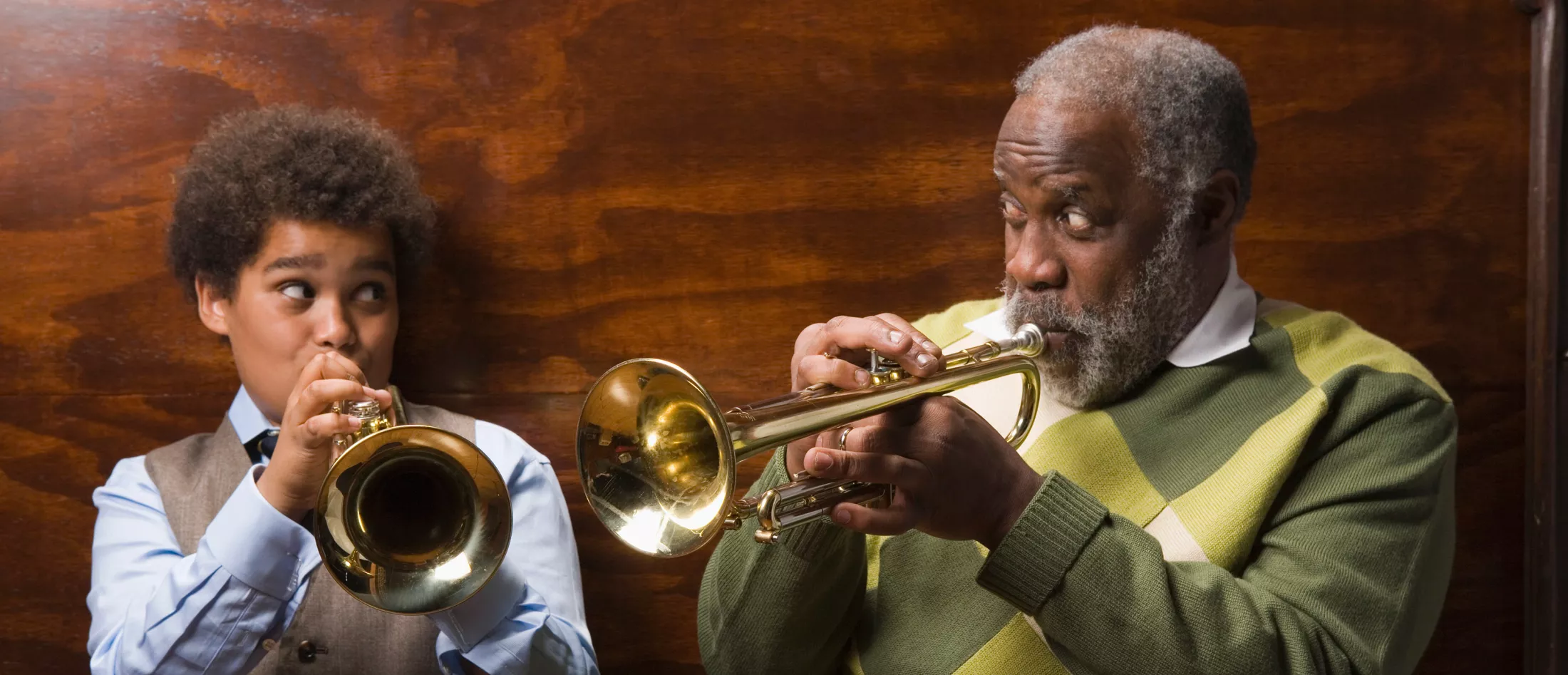 A grandfather and grandson playing trumpets together