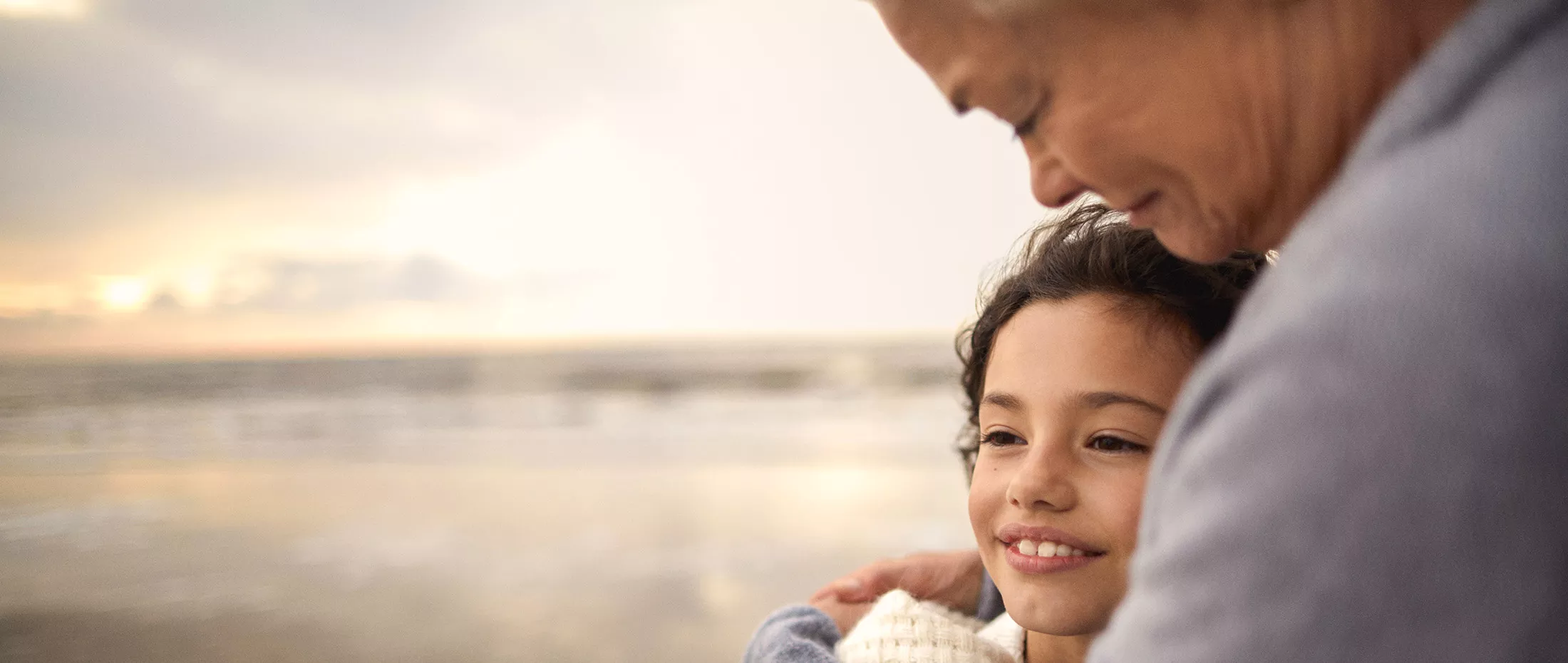 Grandmother embracing granddaughter on the beach