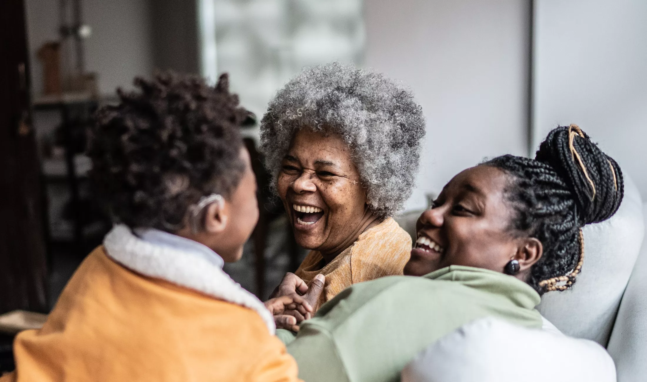 Child playing with mother and grandmother in living room at home 