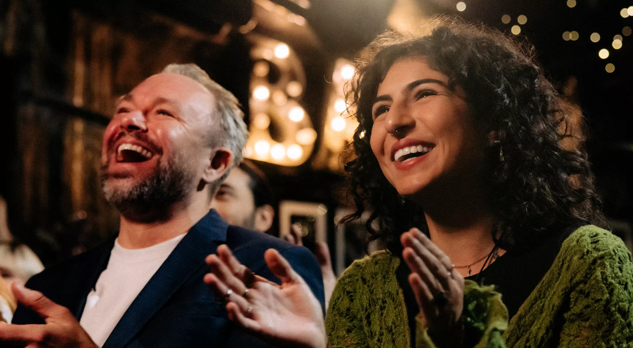 Happy audience laughing and clapping while watching comedy stage show in a theater 