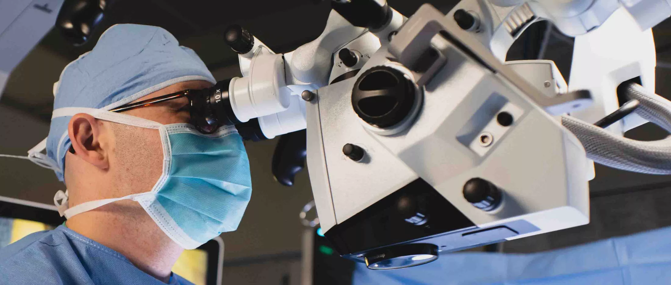 A surgeon in the OR looking through a microscope