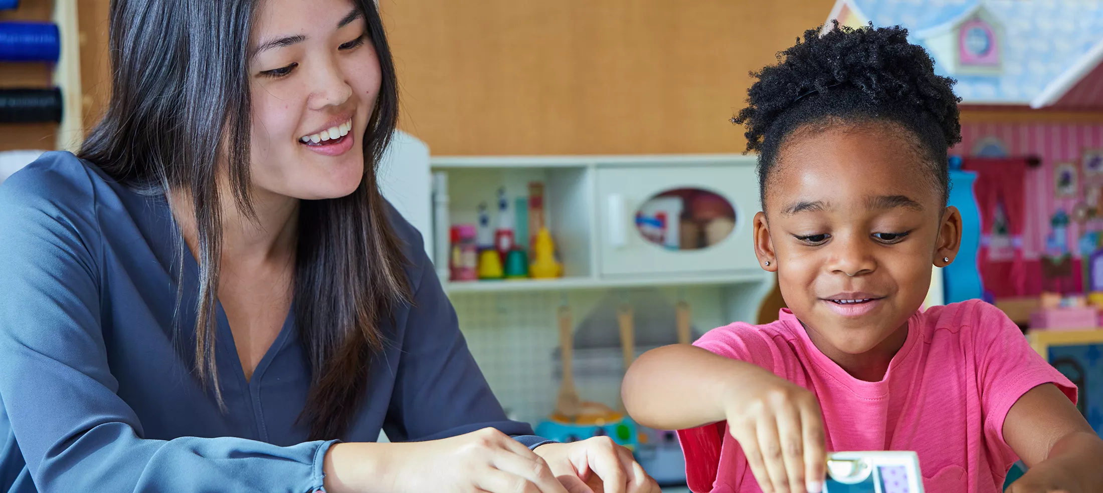 A teacher and child doing a puzzle in a classroom