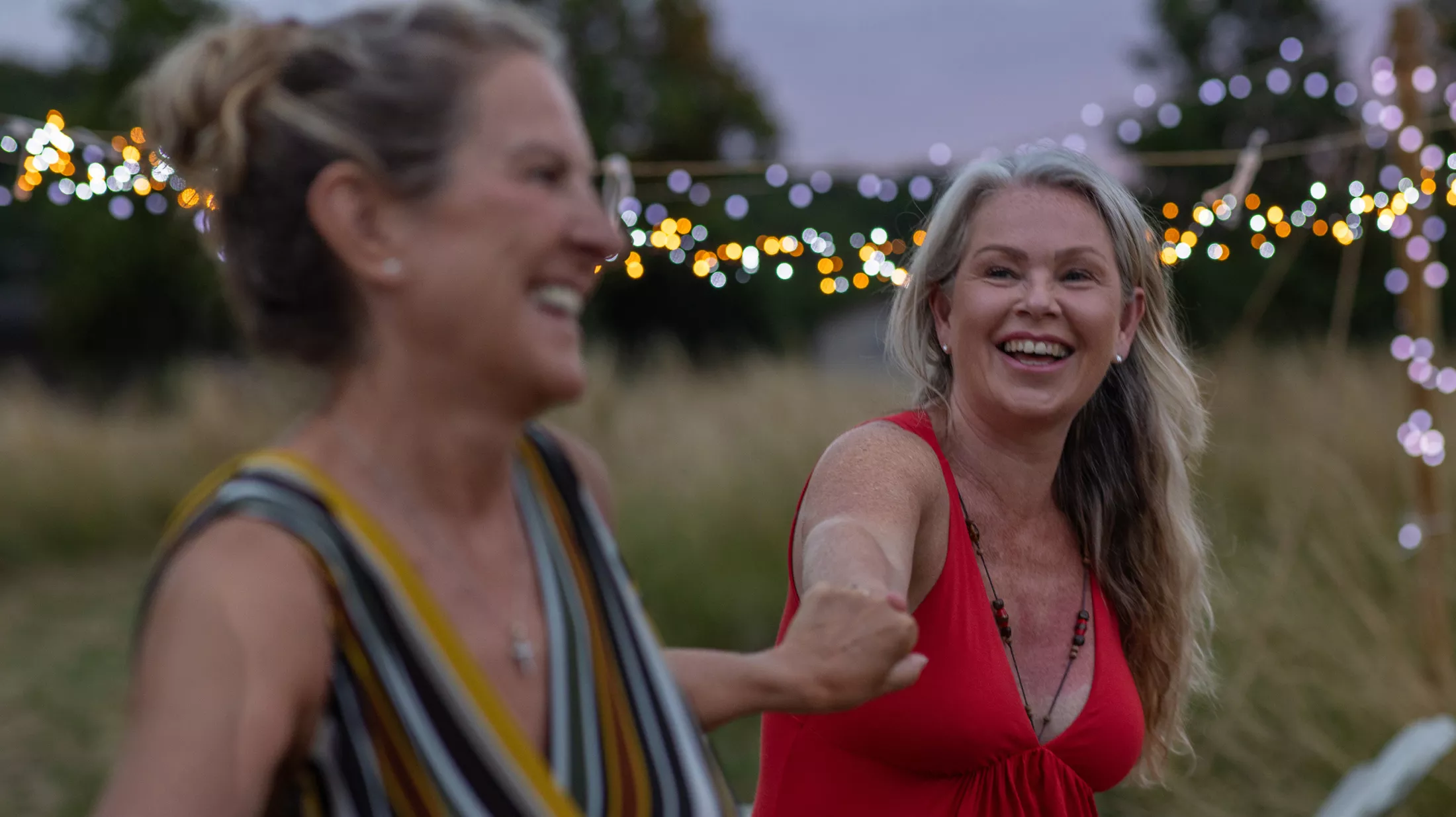 Two older women dancing outside on a Summer evening