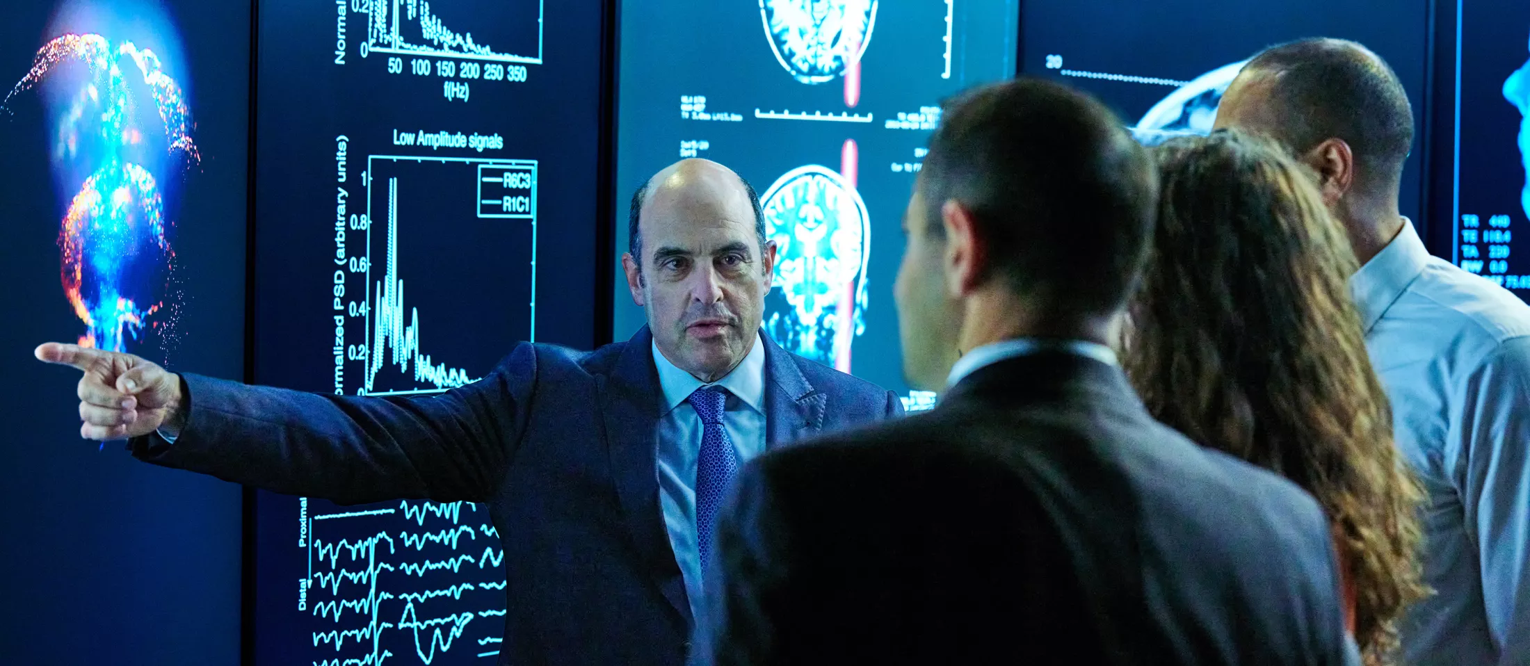 A physician pointing to screens in front of a small group