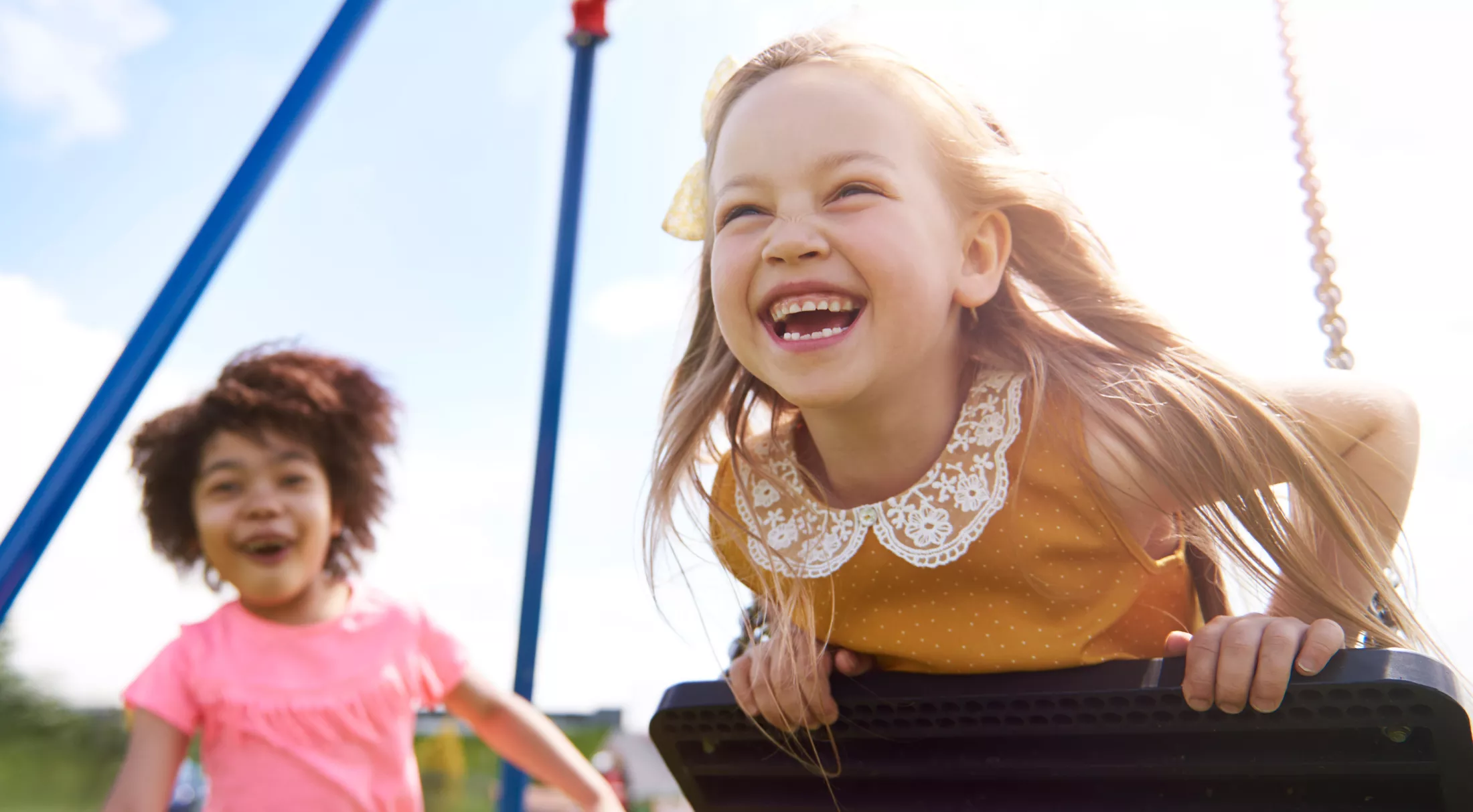 Two girls playing on playground swings