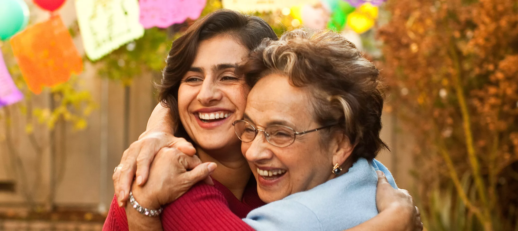 A woman hugging her mother outside at a party