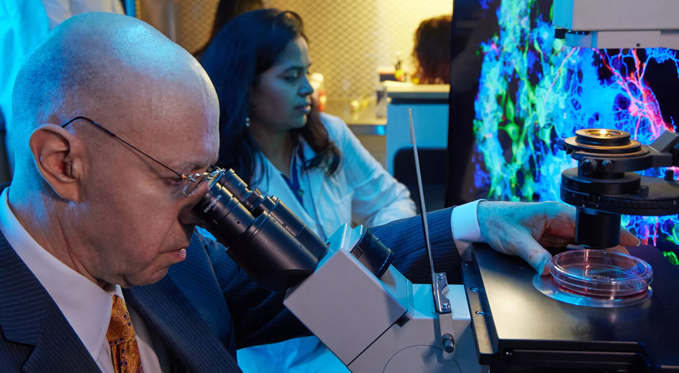 A physician looking into a microscope in a lab