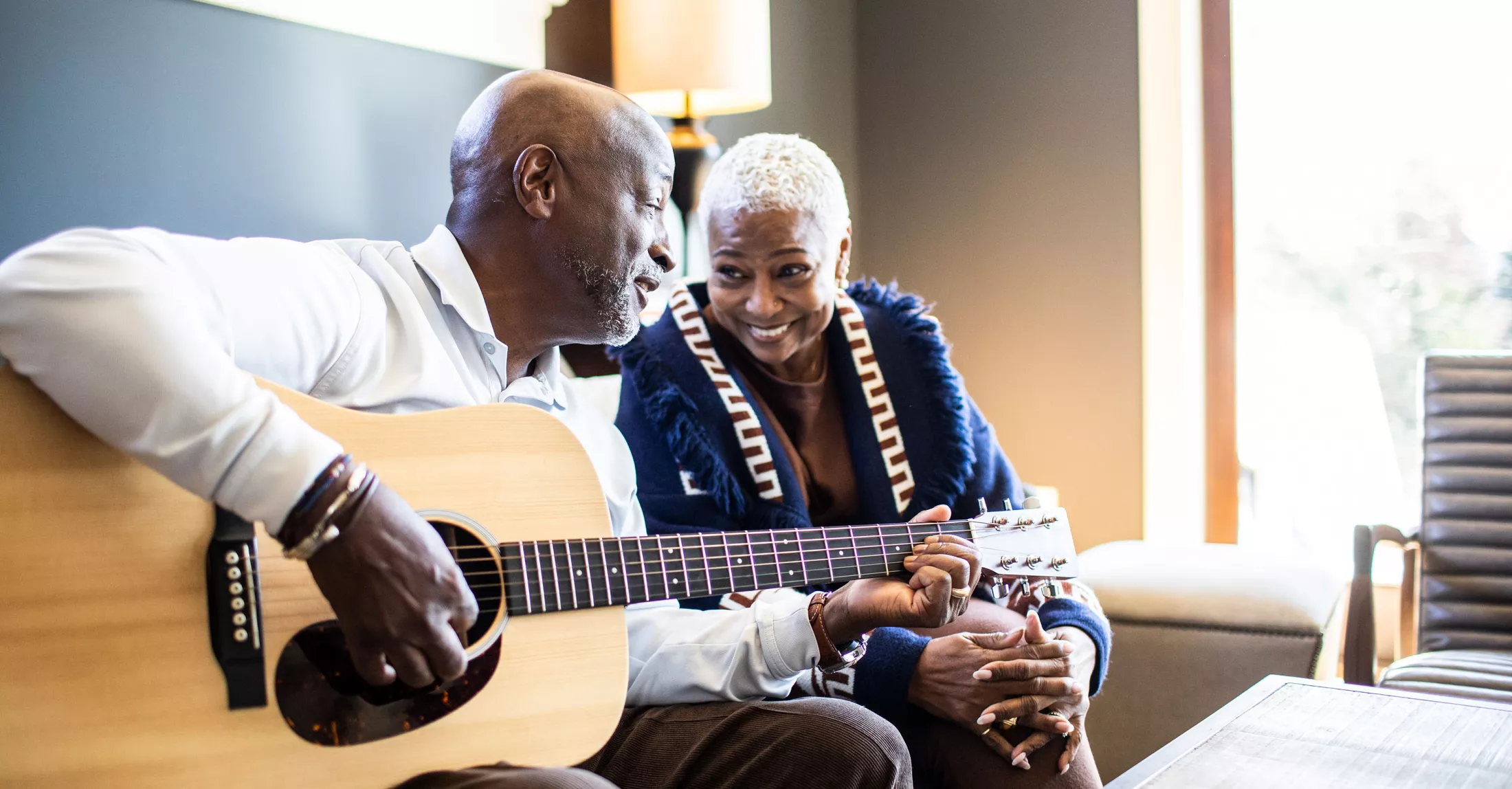 A man playing guitar to his wife at home