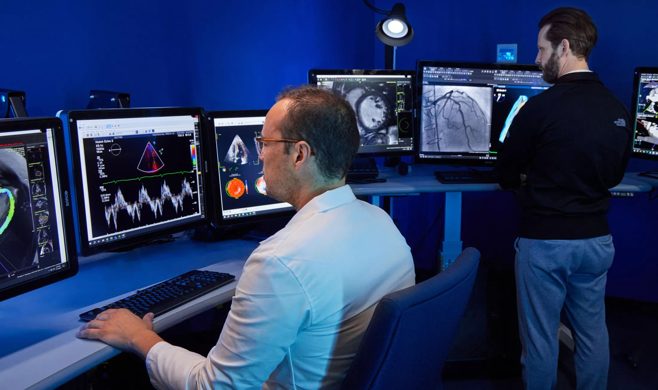 Two people in a lab setting, looking at screens