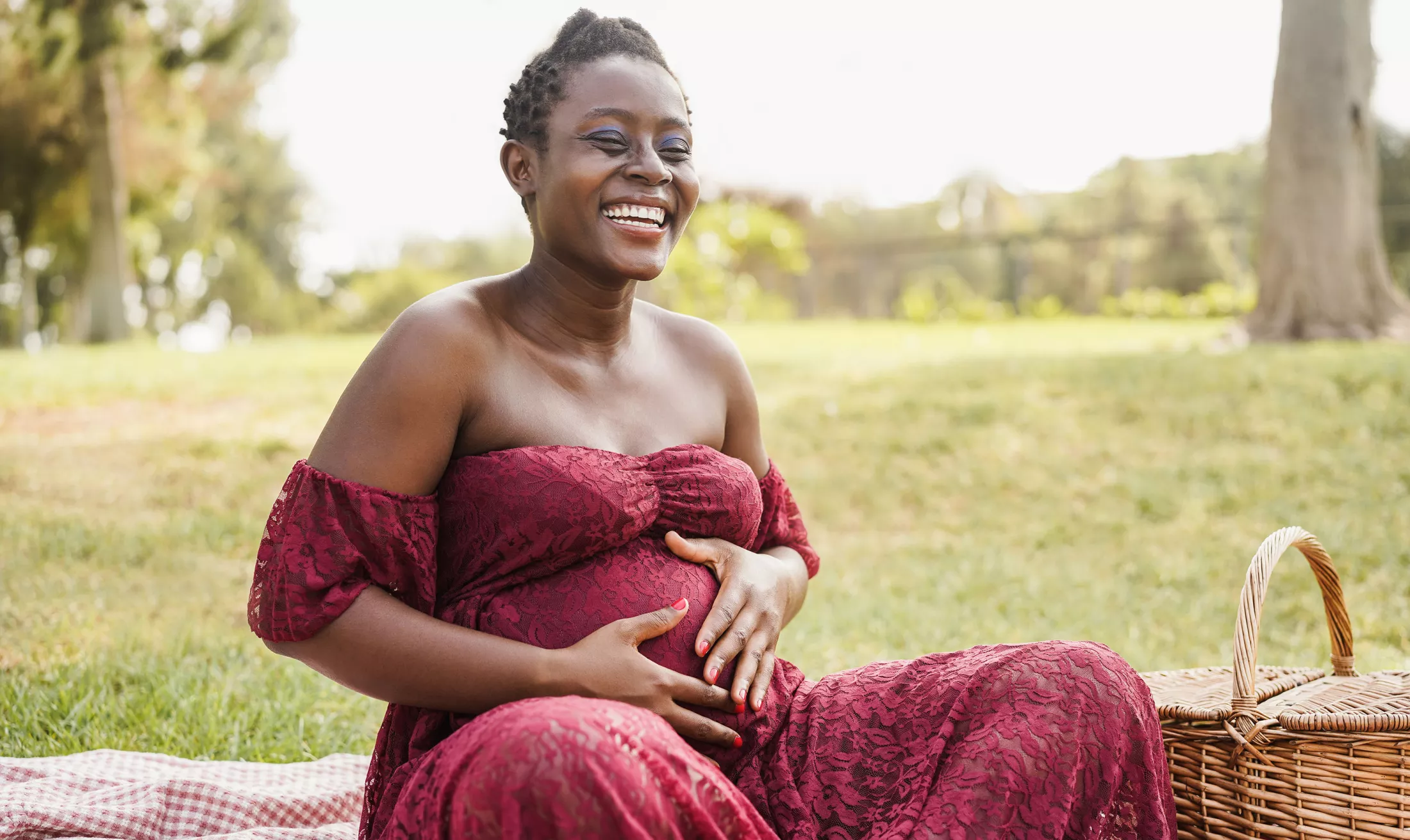 A pregnant woman having a picnic outside in a park