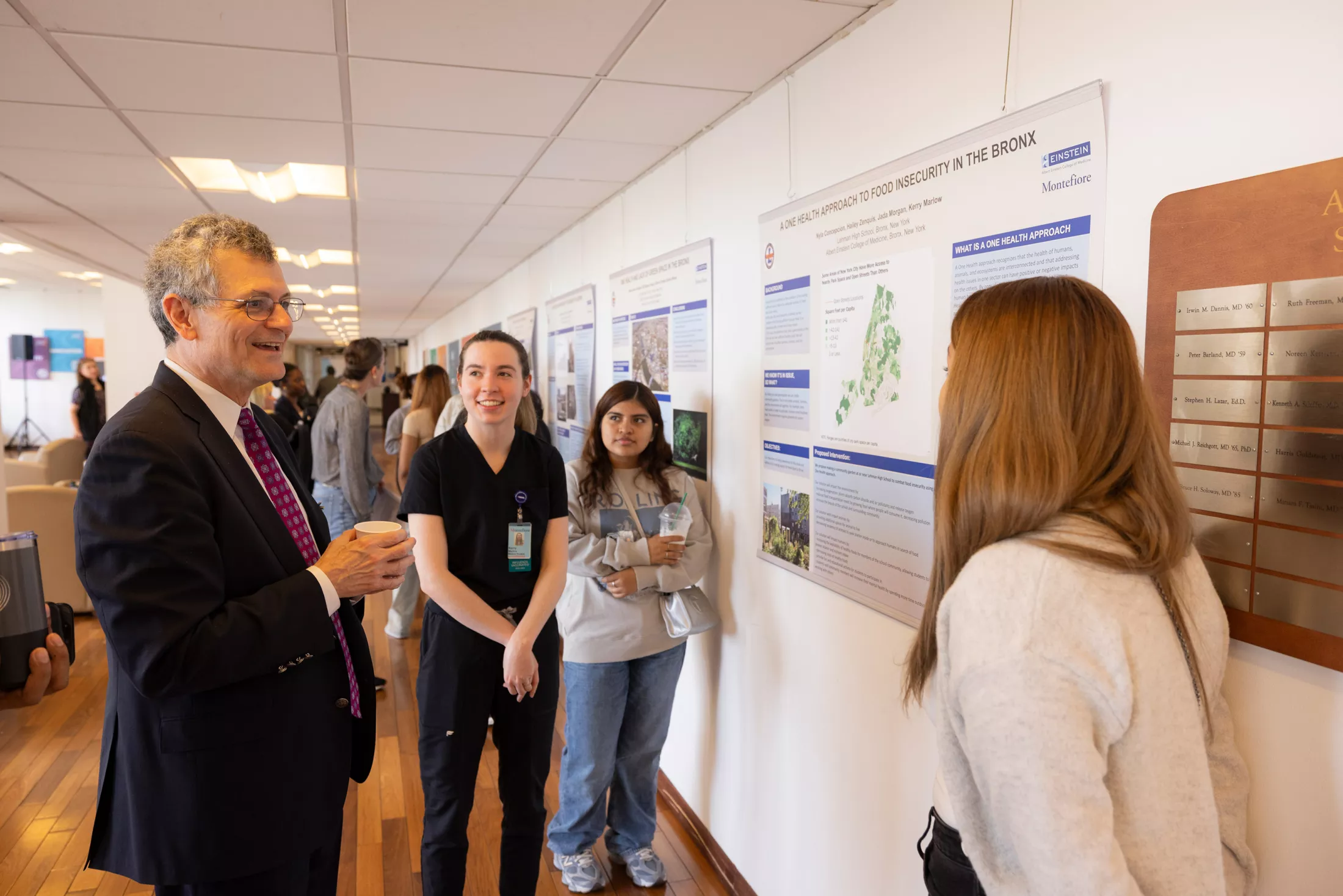 Einstein Dean Yaron Tomer, M.D., discusses a One Health poster with Einstein medical student Kerry Marlow, second from left, and Lehman High School students Jinelly Perez, second from right, and Hailey Zenquist. 