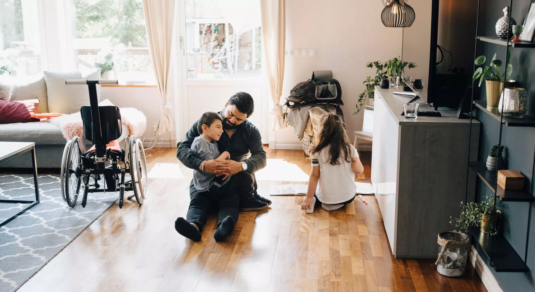 High angle view of father holding autistic son while sitting by daughter on floor at home.