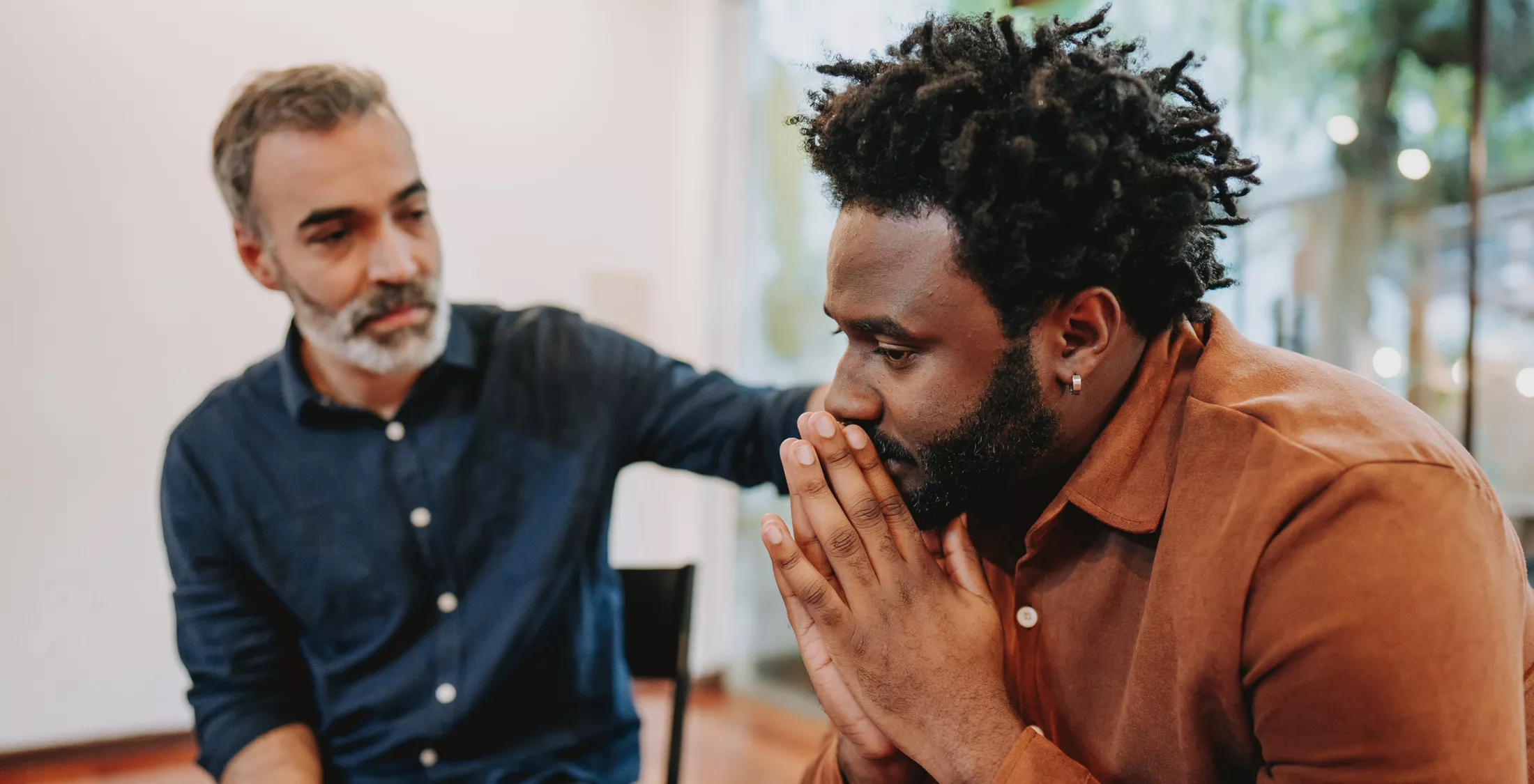 Concerned man being comforted by another in a serious talk