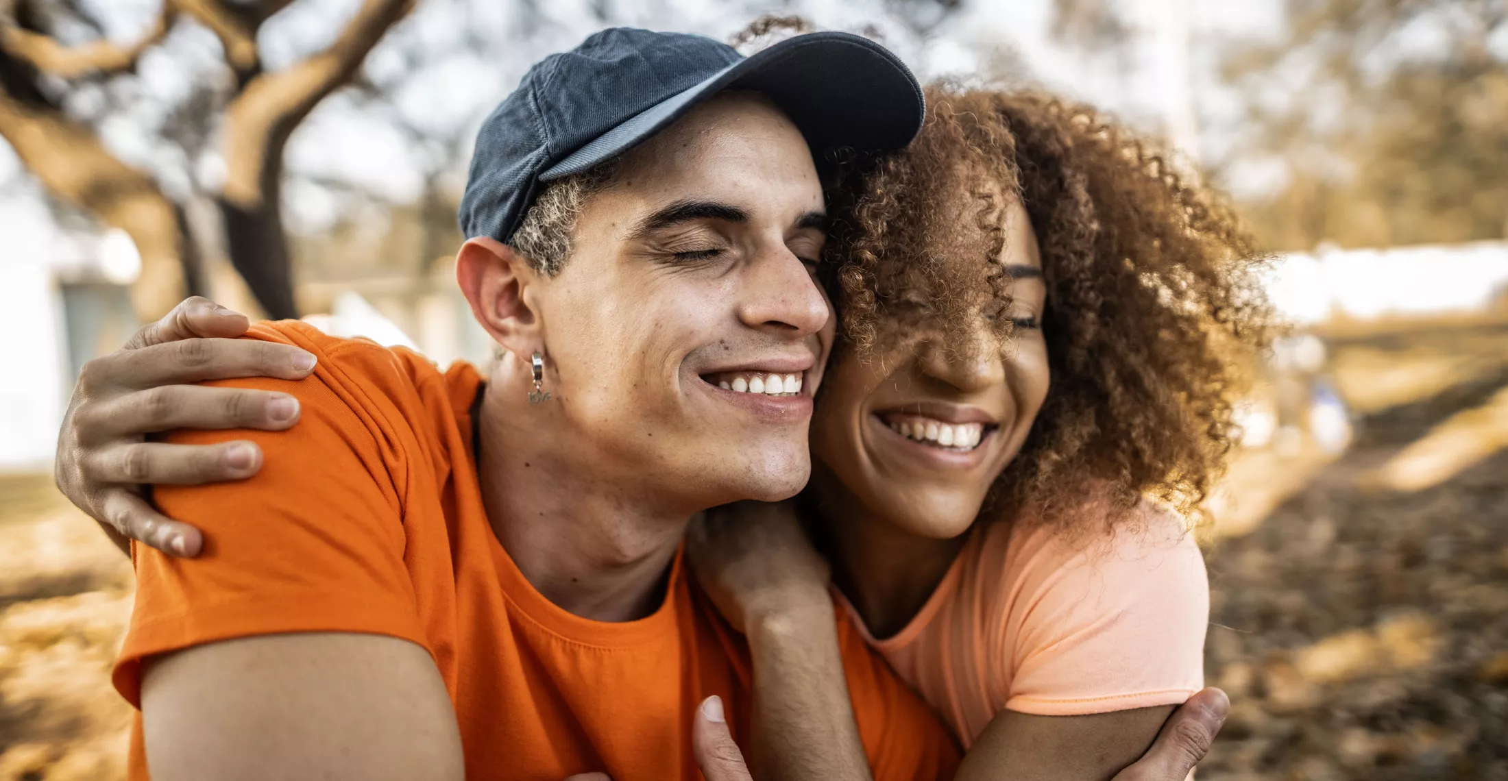 Smiling couple in orange shirts hugging outside