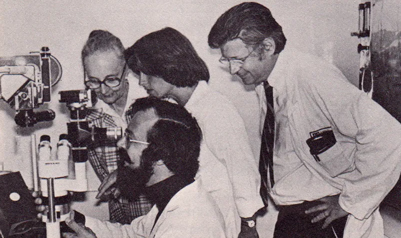 Four scientists observe inner ear growth through a time-lapse microscope in a research lab.
