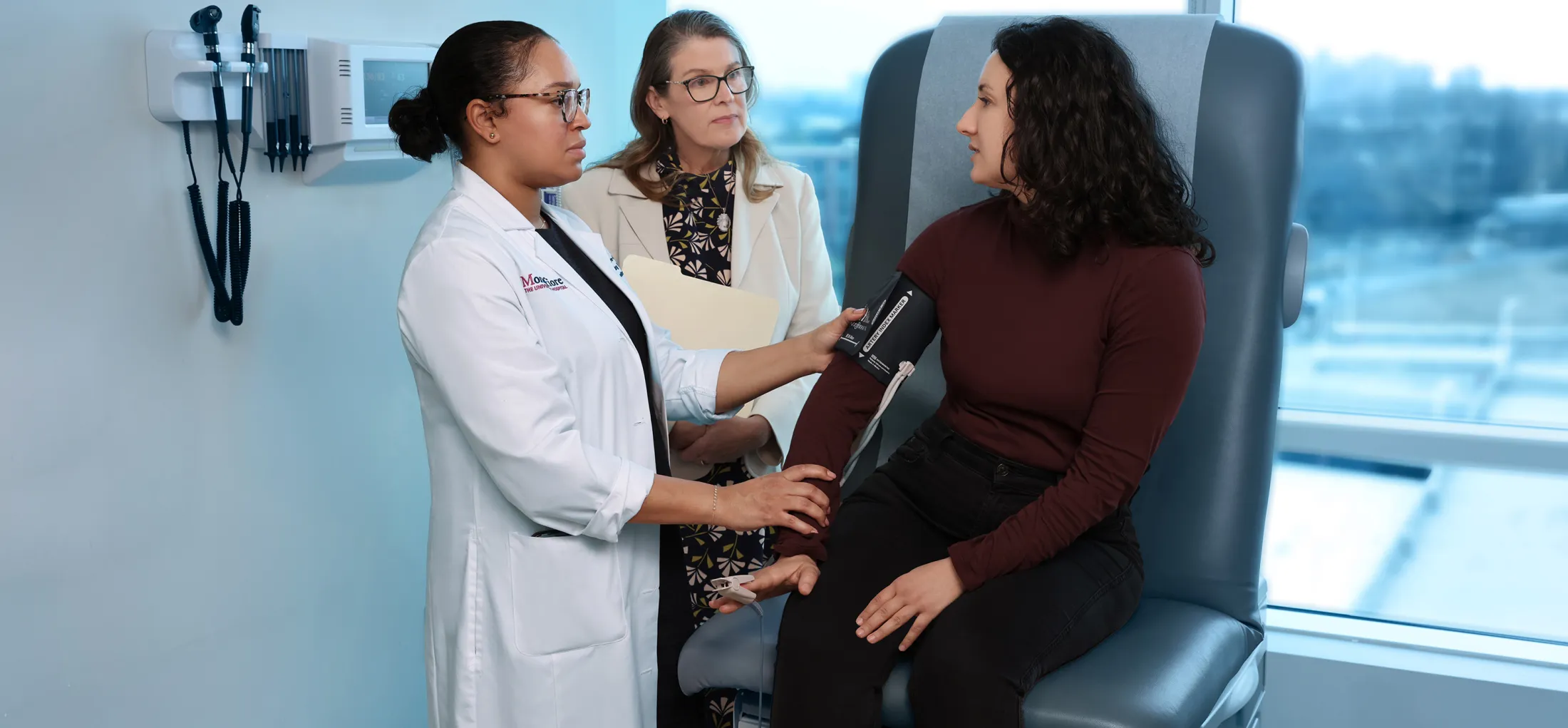 Healthcare provider taking patient’s blood pressure in exam room