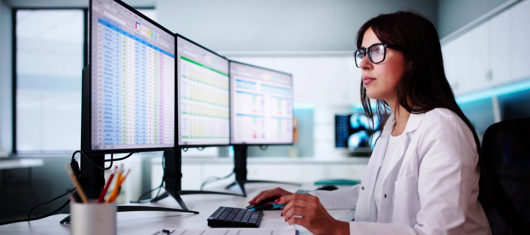 Lab technician in front of three monitors