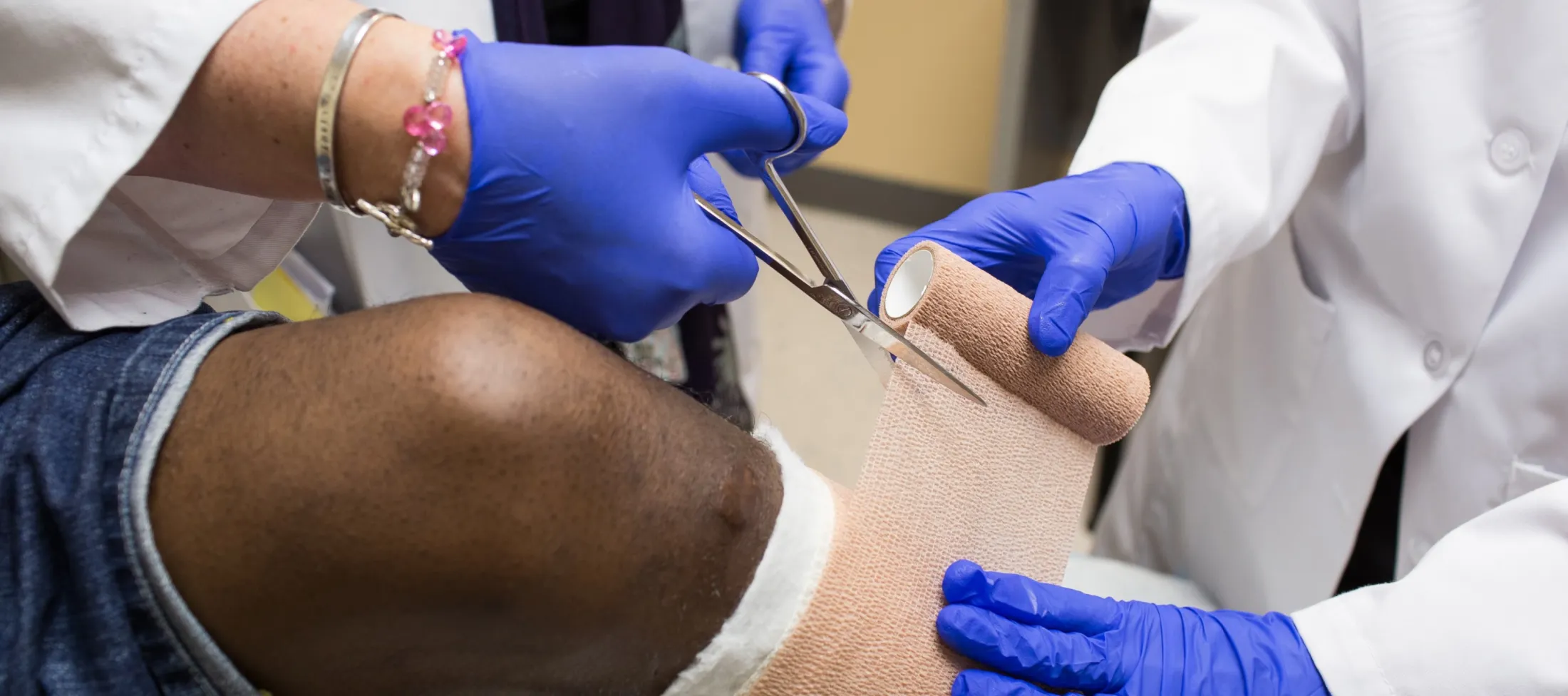 Two doctors dressing up a wounded leg.
