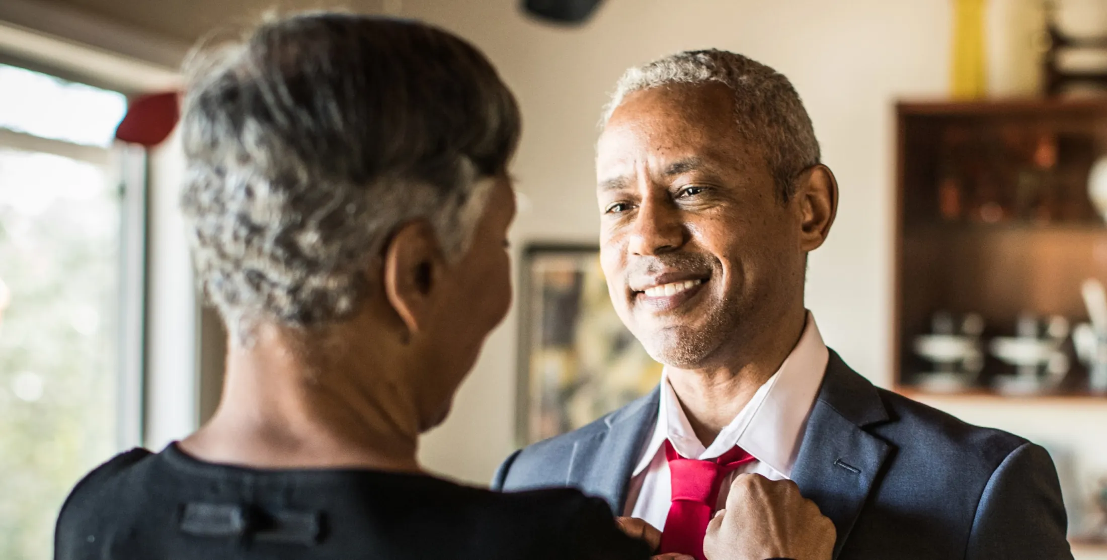 A man smiling at his wife while she fixes his tie