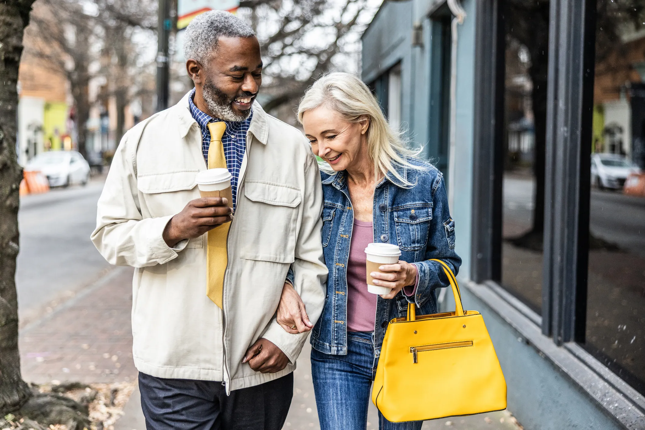 smiling older couple walking together down a city sidewalk