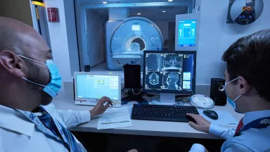 Two doctors discuss results on a computer screen in front of them.