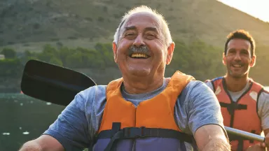 Smiling father and son kayaking on river. 