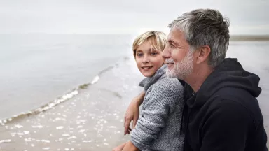 Smiling father and son at the beach on a cloudy day