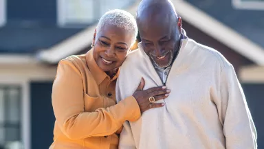 Senior couple walking in front of their home.