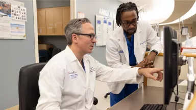 A physician and a student looking at a computer