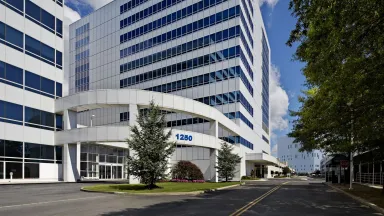 Modern exterior view of Montefiore Hutchinson Campus building, with reflective glass and tree-lined street.