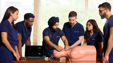 Group of emergency medicine residents practice intubation on a simulation mannequin during a clinical skills session.